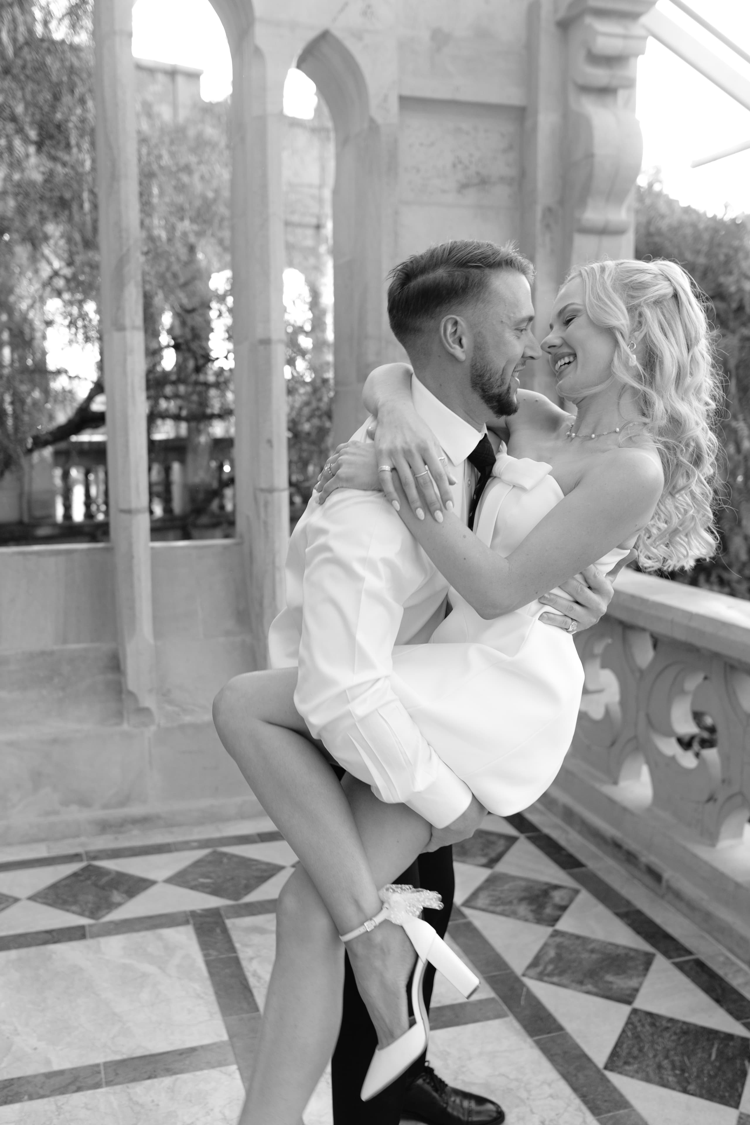 A groom lifts his smiling bride in a romantic embrace at a stone venue