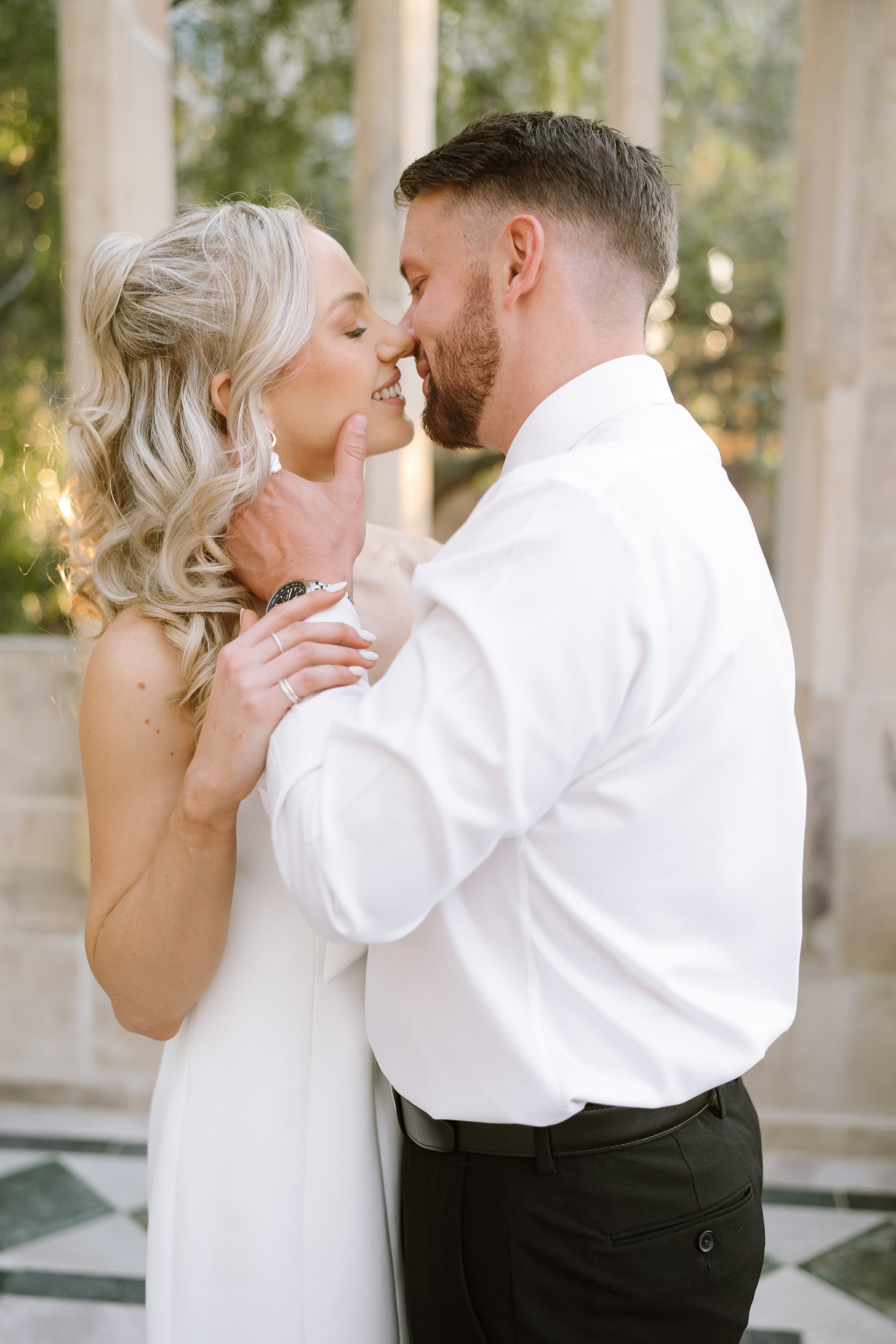 A bride and groom share an intimate moment during their elegant outdoor wedding portrait session