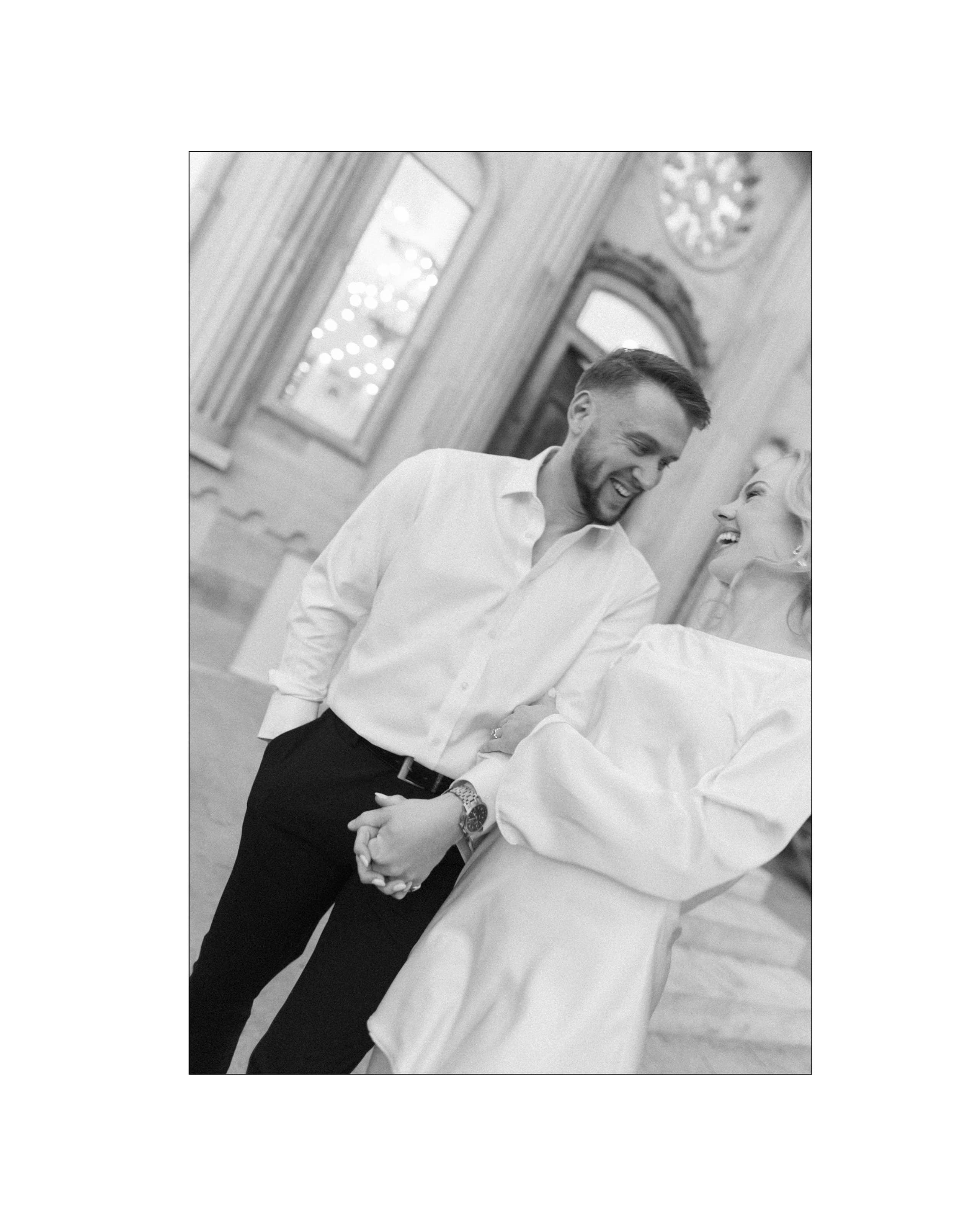 A joyful couple holding hands and laughing together in front of grand architectural columns