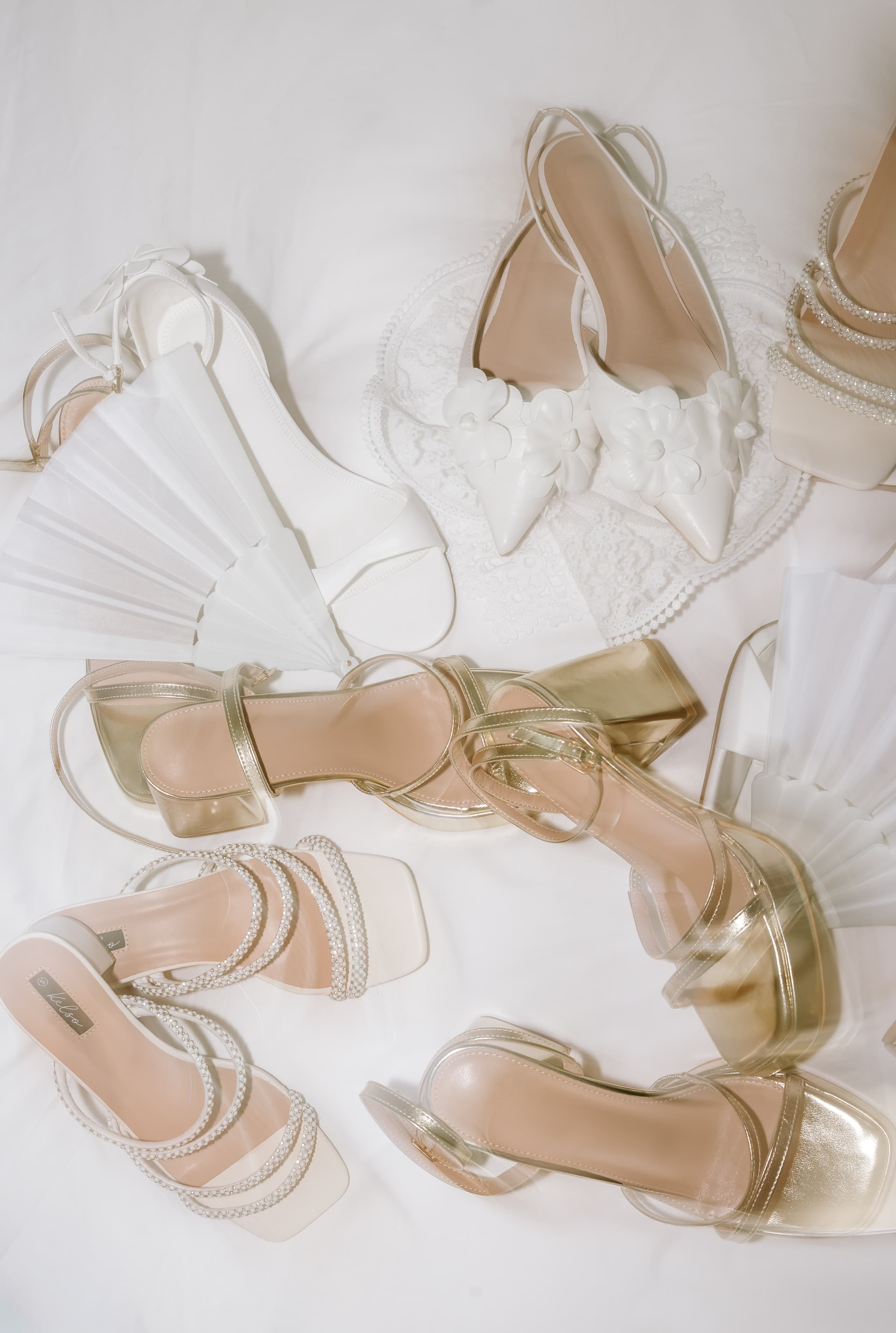 An overhead view of various bridal shoes and wedding accessories arranged on a surface