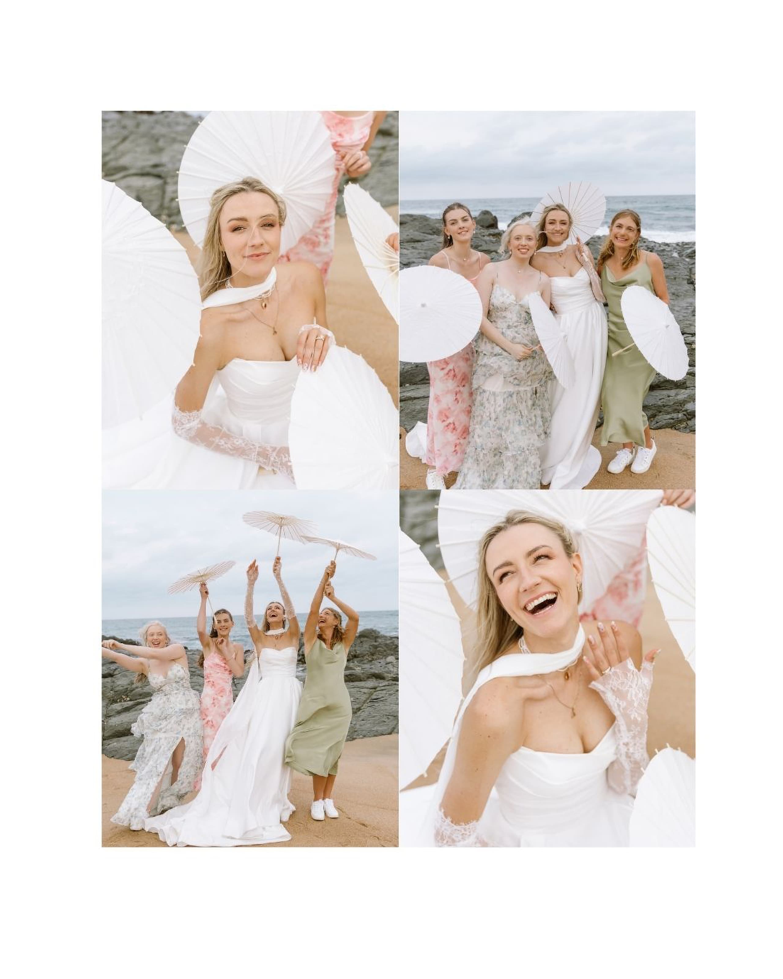 A smiling bride and her bridesmaids pose with white paper parasols on a rocky South African beach