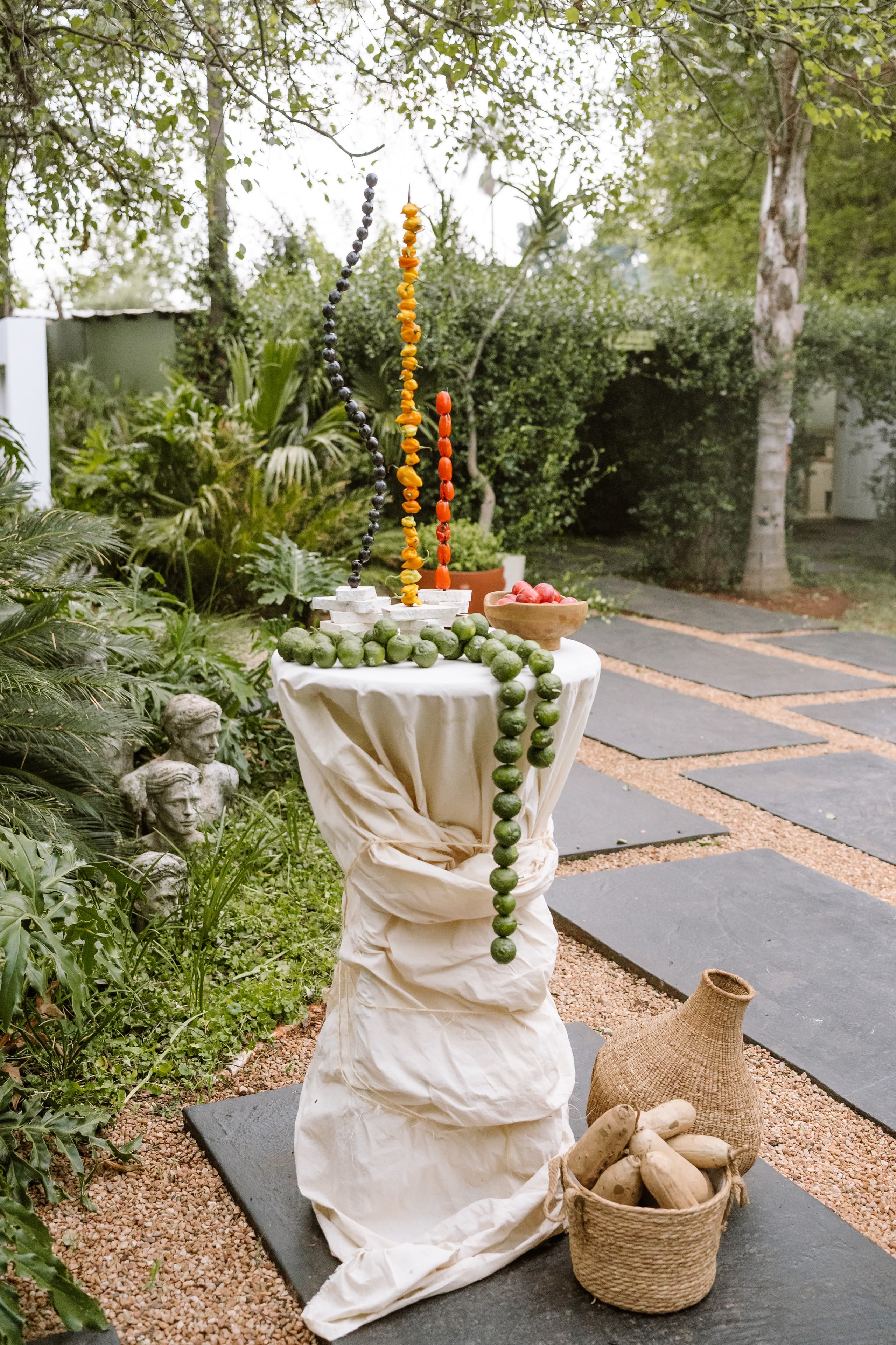 A draped cocktail table features vertical fruit skewers and a garland of green citrus fruits