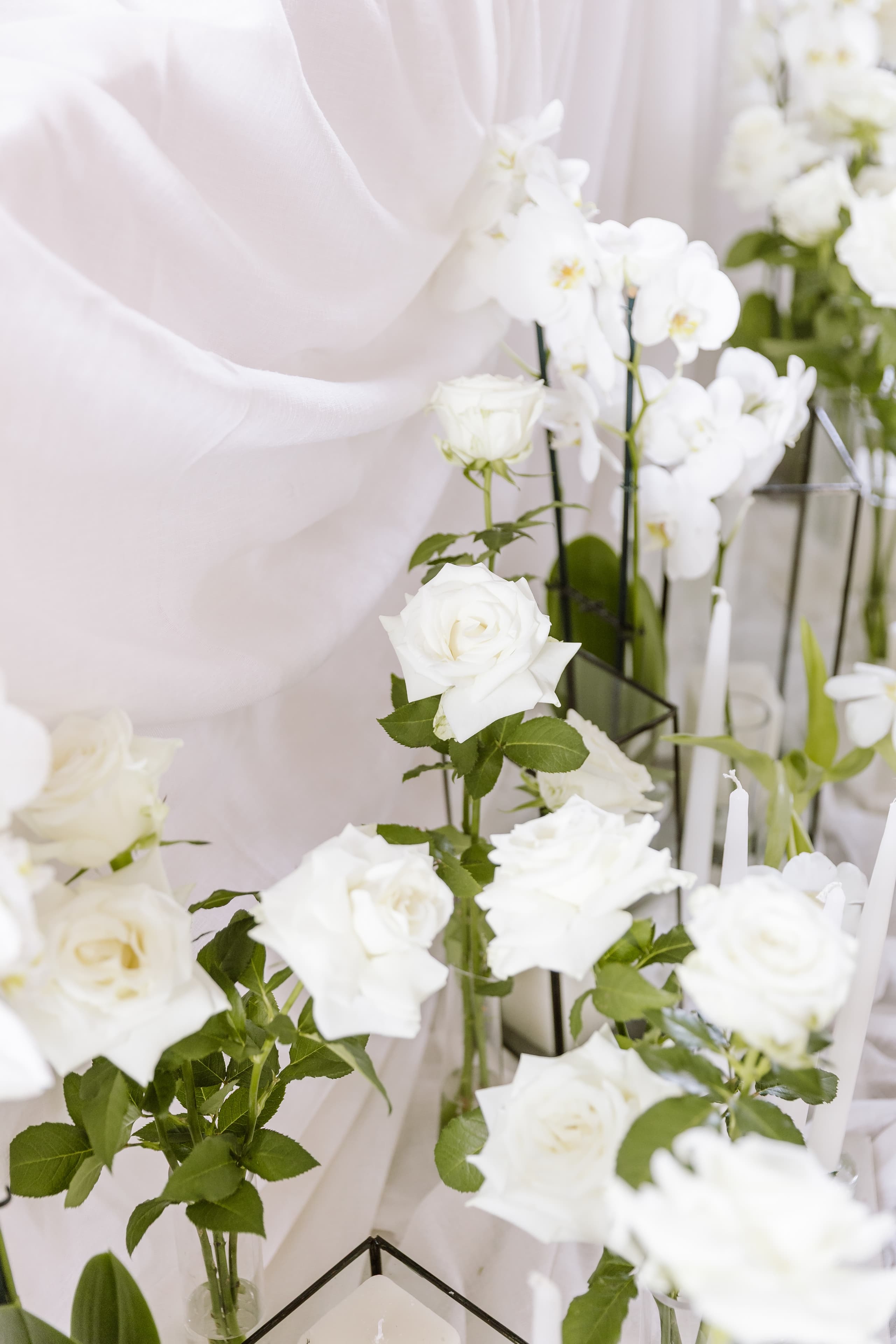 Elegant white roses and orchids arranged in glass vases for a luxury wedding ceremony setting