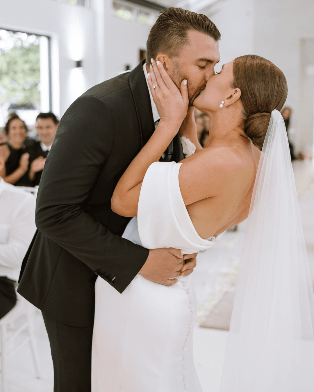A newlywed couple shares a romantic kiss during their elegant indoor wedding ceremony in South Africa