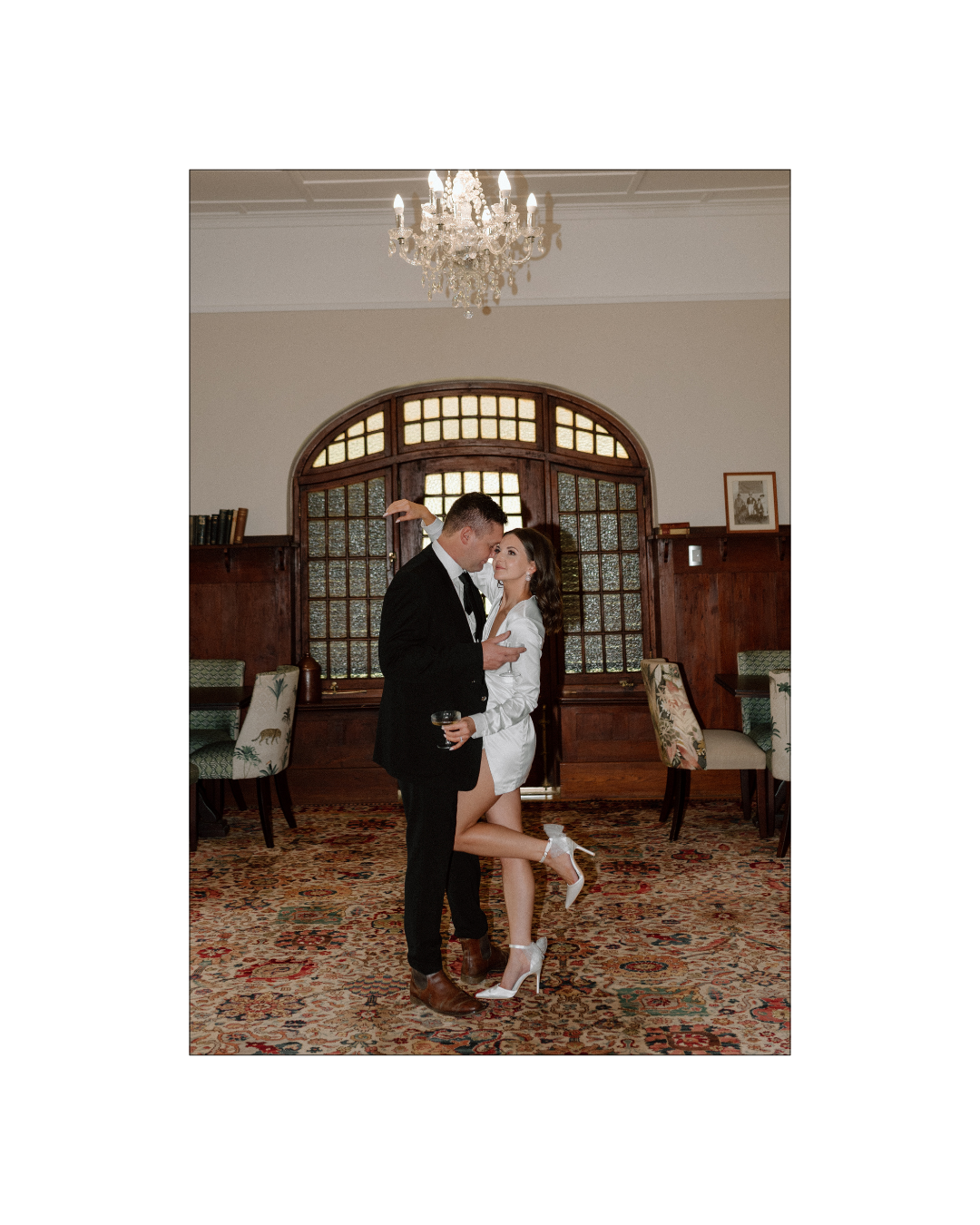 A bride and groom embrace affectionately in a vintage room with ornate patterned carpeting