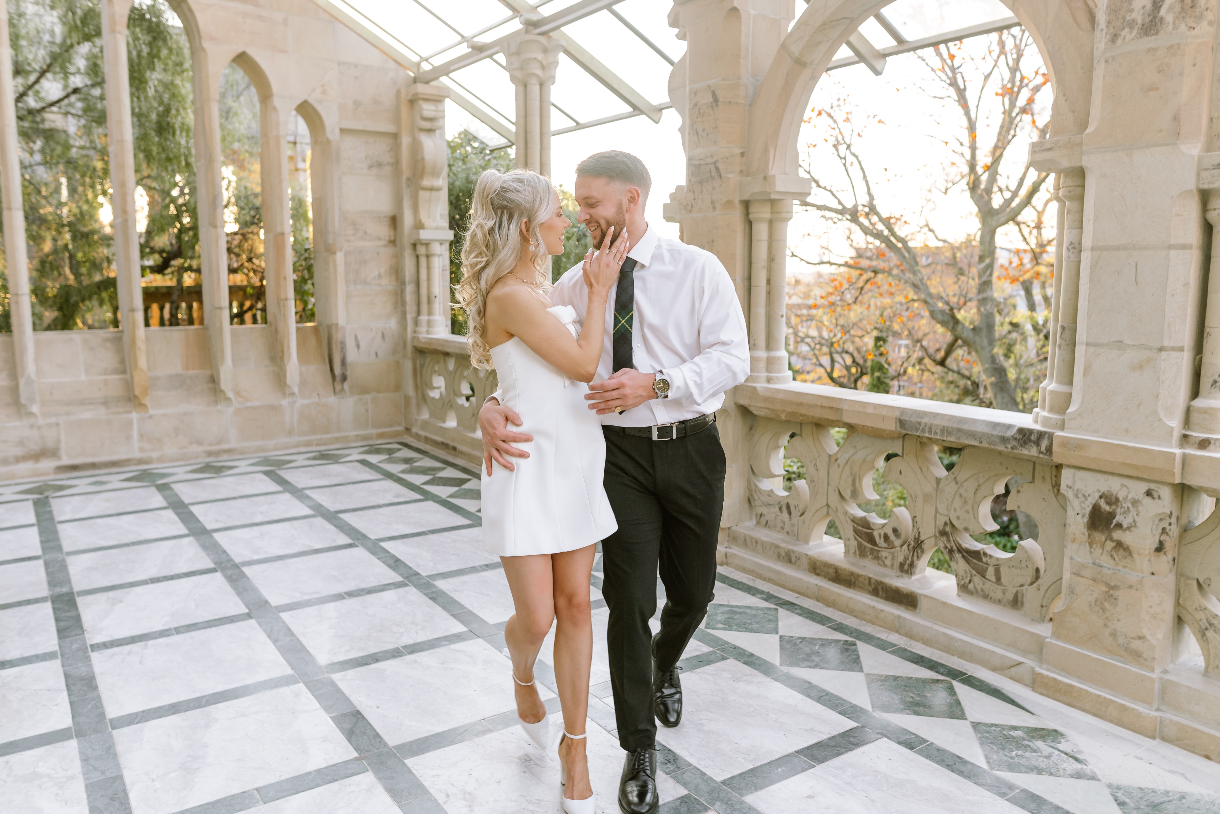 A stylish couple walks together on a marble balcony during their luxury South African wedding