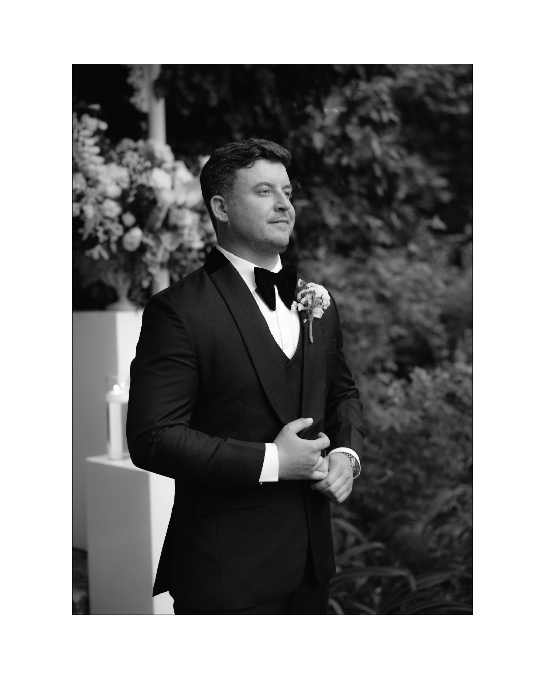 A groom in a black tuxedo stands outdoors during a wedding ceremony in South Africa
