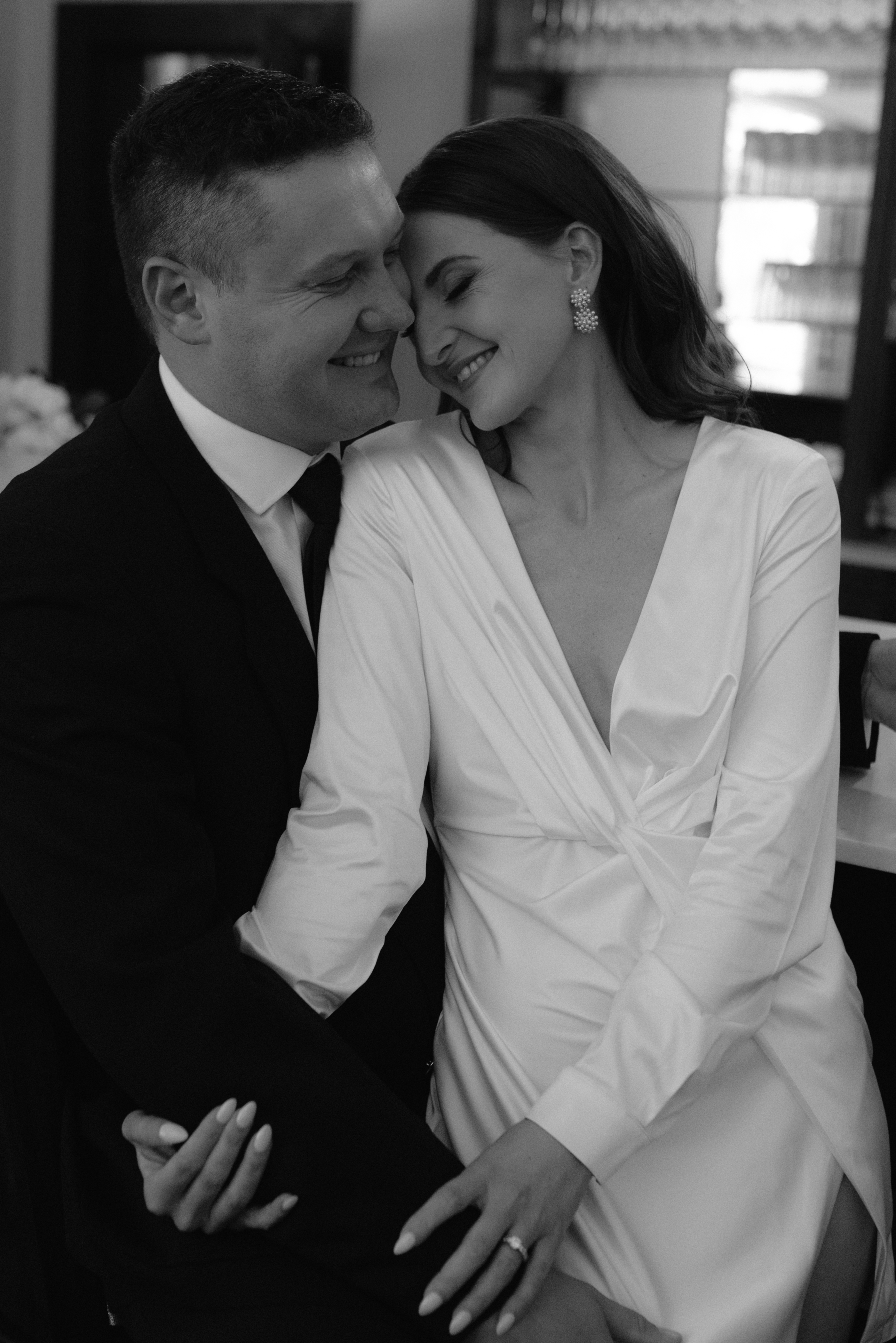 A smiling bride and groom share an intimate moment together in elegant wedding attire