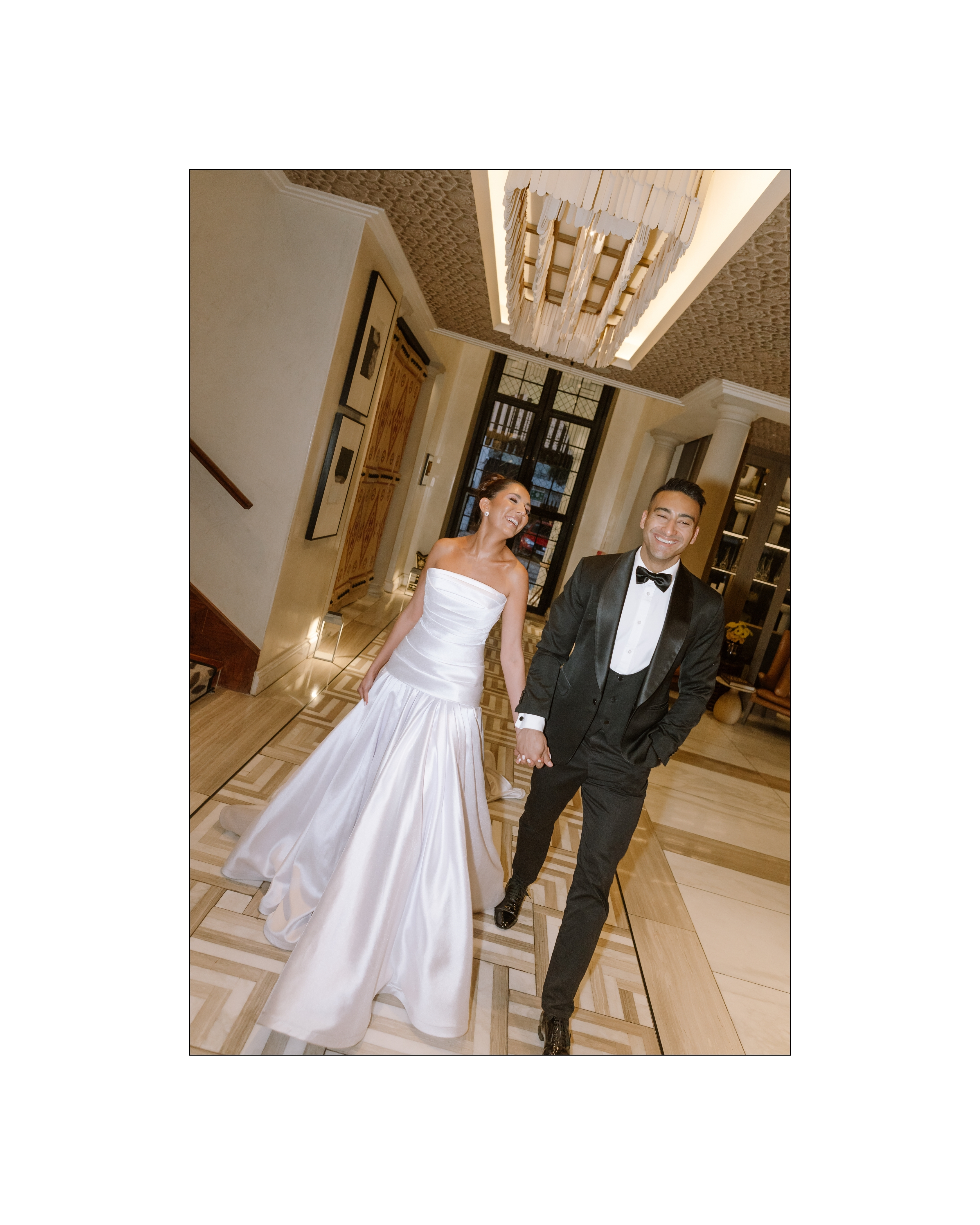 A joyful bride and groom walk hand in hand through a luxurious hotel lobby