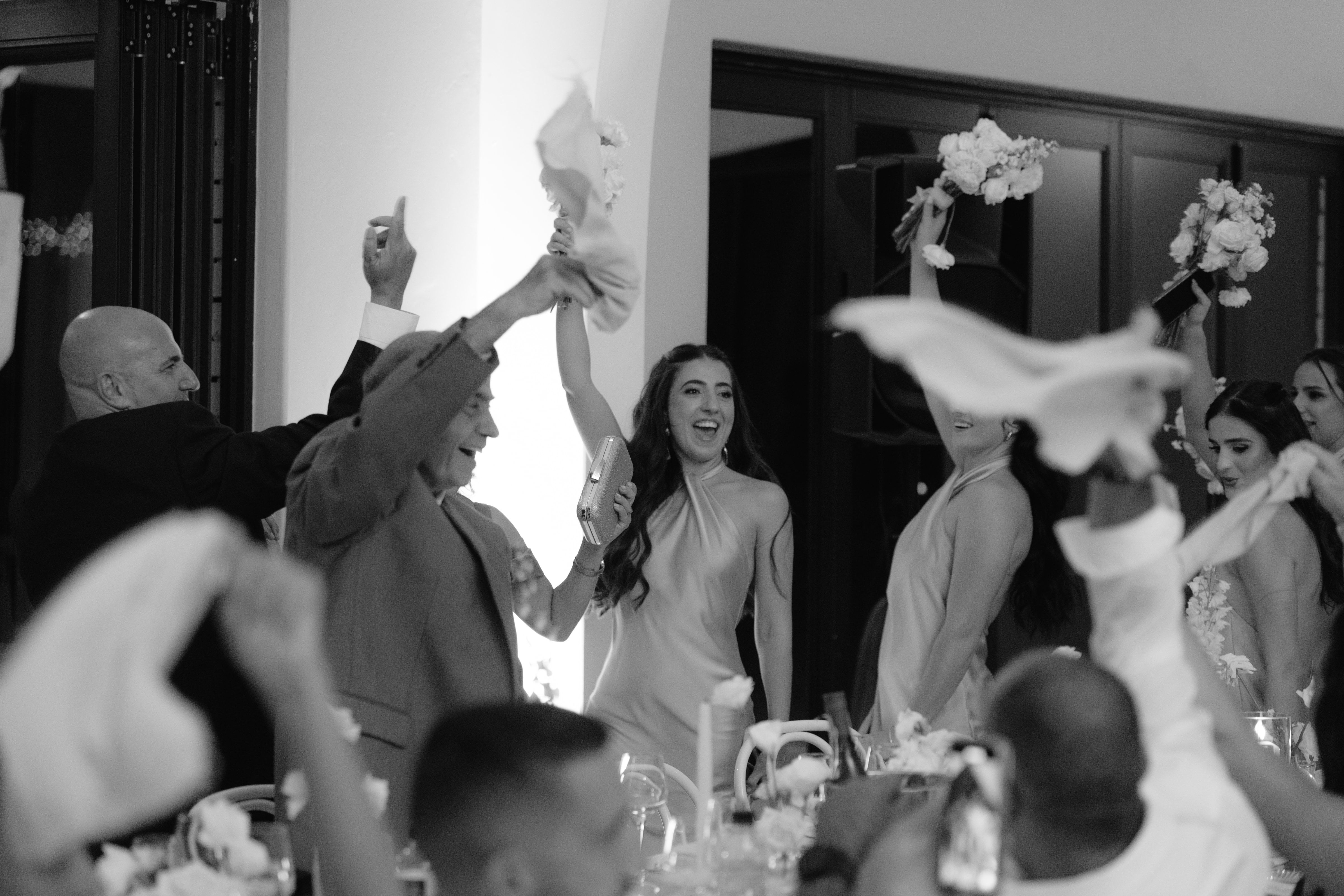 Guests joyfully celebrate at a wedding reception by waving white napkins in the air