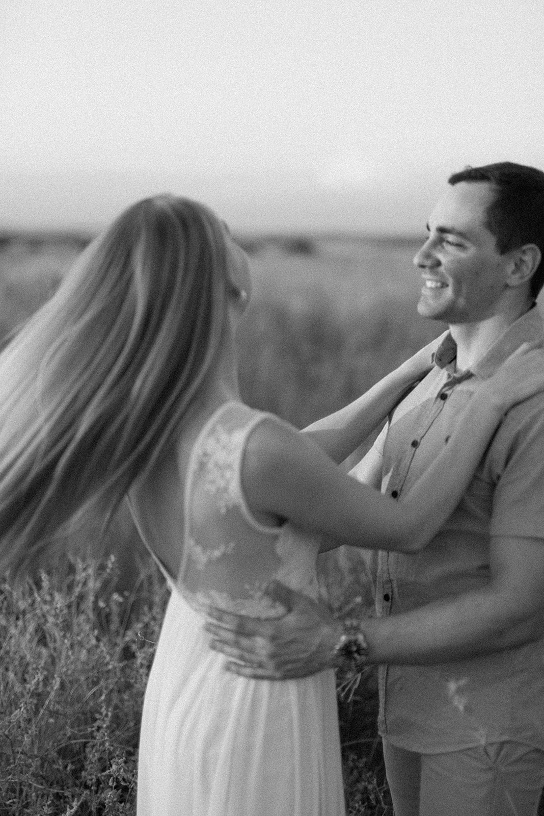A bride with long hair flowing as she dances with her groom in a field